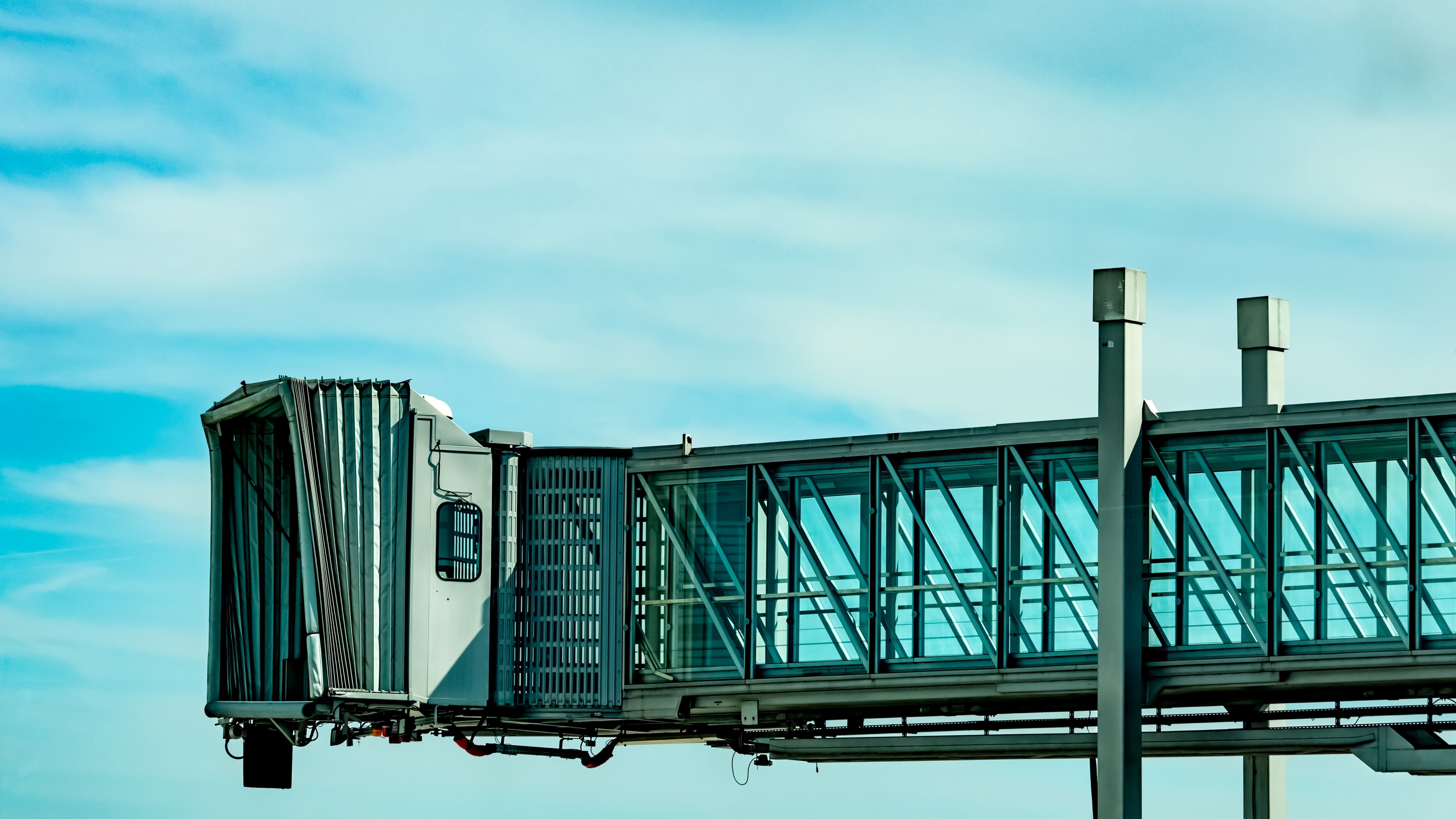 a jet bridge against blue sky and white clouds.