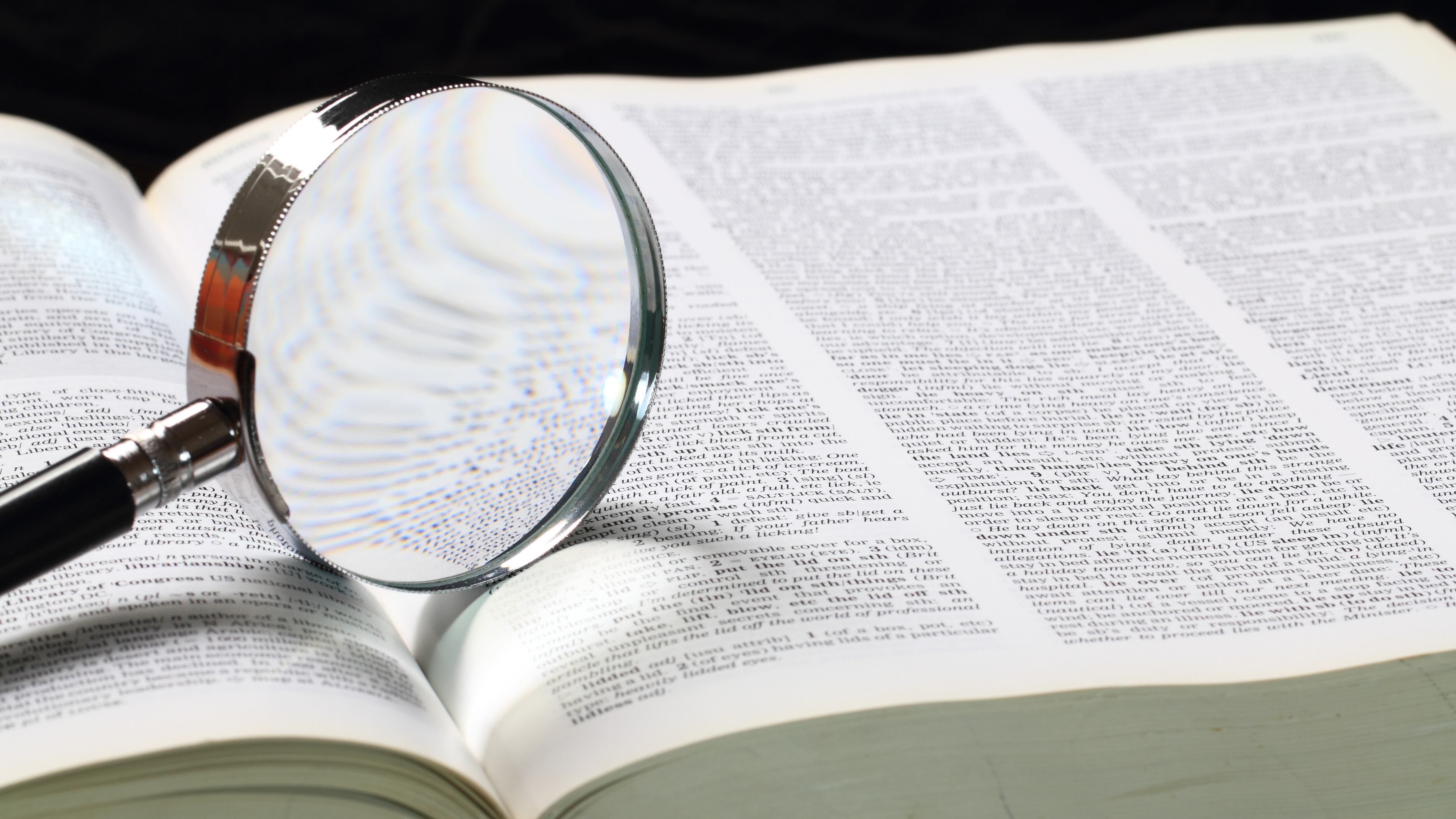 Dictionary with an magnifying glass on top