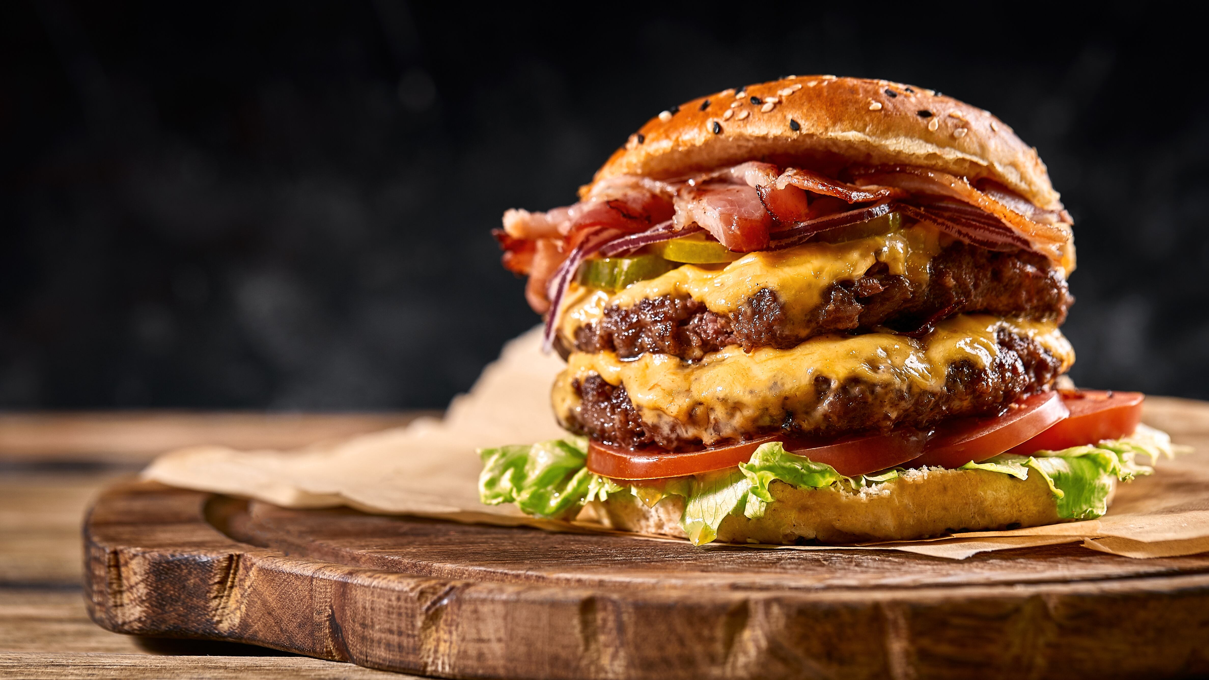 Juicy American burger, hamburger or cheeseburger with two beef patties, with sauce and basked on a black background.