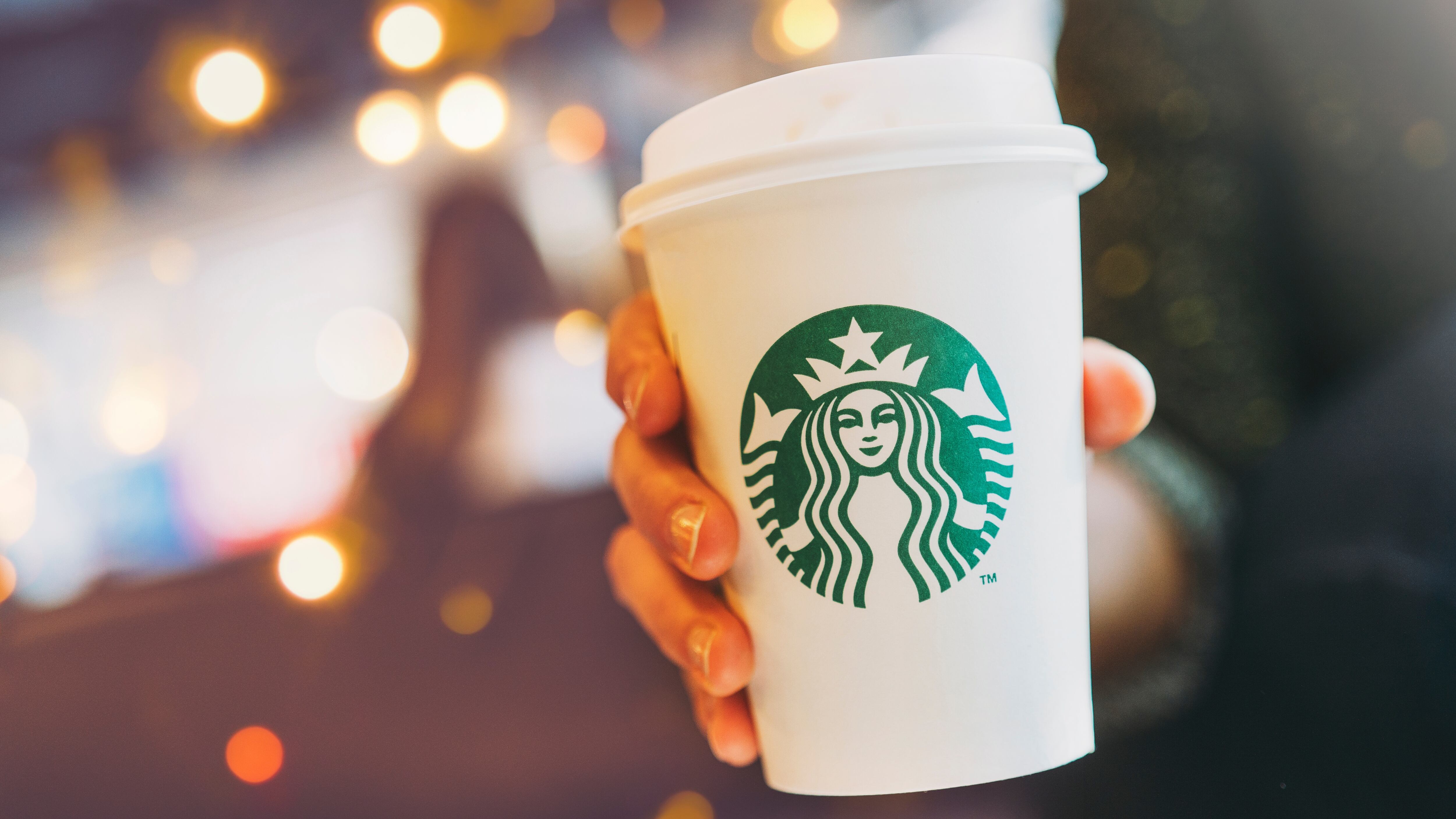 Close up of a Woman drinking a tall Starbucks coffee in starbucks coffee shop with carrot cake. Starbucks is the world's largest coffee house with over 20,000 stores in 61 countries.
