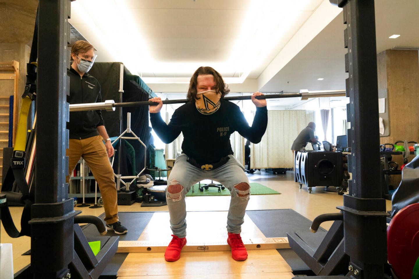 Physical therapist Eric Ross, left, watches as Joe DiMeo lifts weights, Monday, Jan. 25, 2021 at NYU Langone Health in New York. The 22-year-old New Jersey resident had a face and double hand transplant operation last August, two years after being badly burned in a car crash.  “I knew it would be baby steps all the way,” DiMeo said of his recovery. “You’ve got to have a lot of motivation, a lot of patience. And you’ve got to stay strong through everything.” (AP Photo/Mark Lennihan)